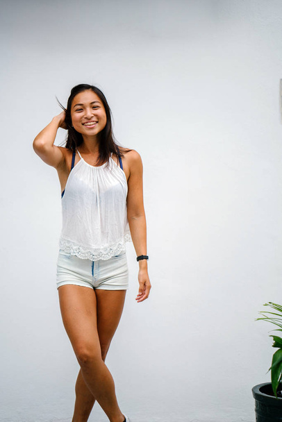 Portrait of a candid moment for an young, athletic and tanned Chinese Asian woman. She is smiling and is dress casually and comfortably. - Foto, afbeelding