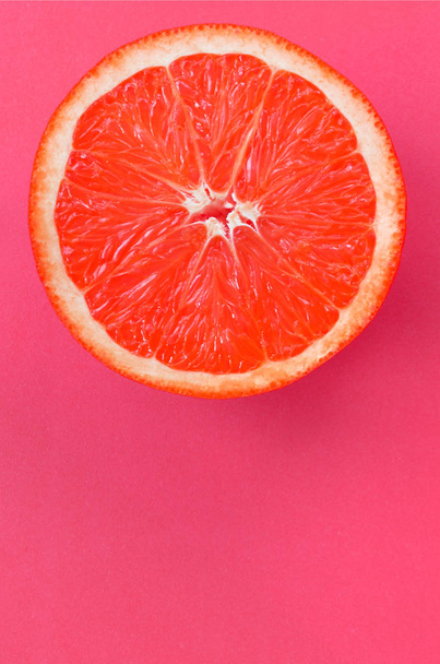 Vista superior de una rodaja de pomelo sobre fondo brillante en color rosa. Una imagen de textura cítrica saturada
 - Foto, imagen
