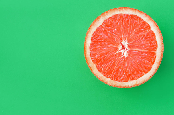 Вид сверху одного грейпфрута на ярком фоне зеленого цвета. Насыщенное цитрусовое изображение
 - Фото, изображение