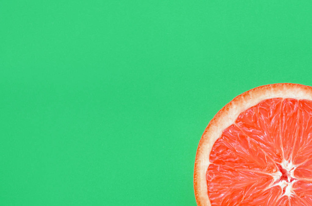 Вид зверху на один шматочок грейпфрута на яскравому фоні в зеленому кольорі. Зображення насиченої цитрусової текстури
 - Фото, зображення