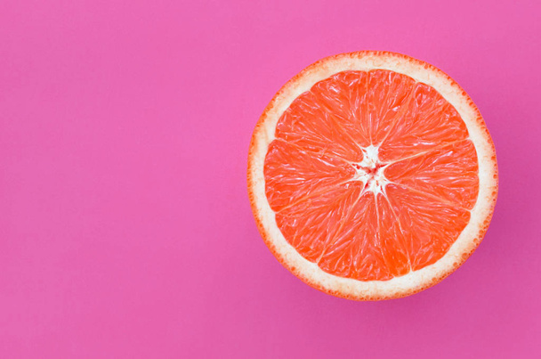 Top view of an one grapefruit slice on bright background in purple color. A saturated citrus texture image - Foto, Imagem