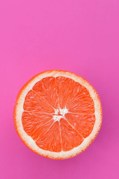 Вид зверху на один шматочок грейпфрута на яскравому фоні фіолетового кольору. Зображення насиченої цитрусової текстури
 - Фото, зображення