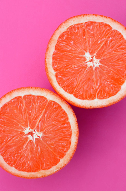 Top view of a several grapefruit slices on bright background in purple color. A saturated citrus texture image - Photo, Image