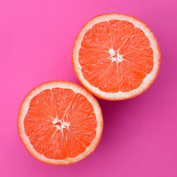 Top view of a several grapefruit slices on bright background in purple color. A saturated citrus texture image - Foto, Bild