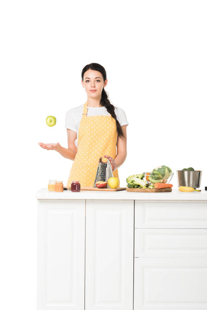 Młoda kobieta rzucając się apple na stole z owoców i warzyw na białym tle  - Zdjęcie, obraz