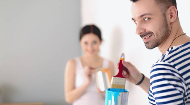 Portrait of happy smiling young couple painting interior wall of new house. young couple - Foto, afbeelding