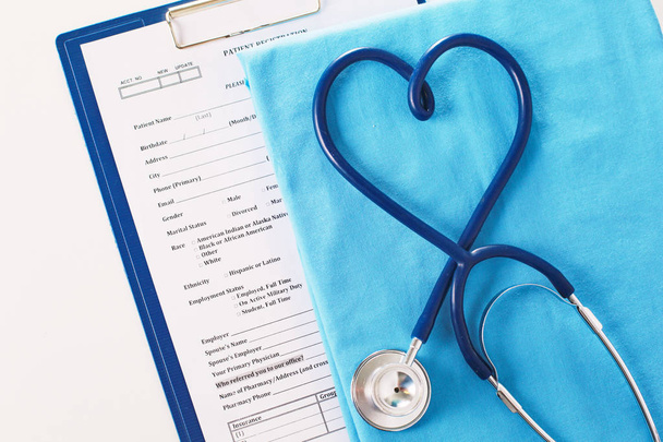 Een stethoscoop vormgeven van een hart op een medische uniform, close-up, selectieve aandacht - Foto, afbeelding