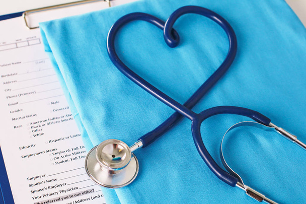 A stethoscope shaping a heart on a medical uniform, closeup, selective focus - Photo, image