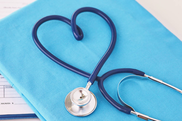 Een stethoscoop vormgeven van een hart op een medische uniform, close-up, selectieve aandacht - Foto, afbeelding