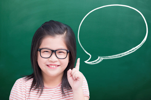 cute girl showing  something with speech bubble on green chalkboard - Photo, Image