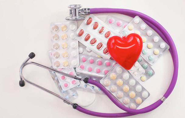 Tabletten, stethoscoop en hart liggen op tafel - Foto, afbeelding