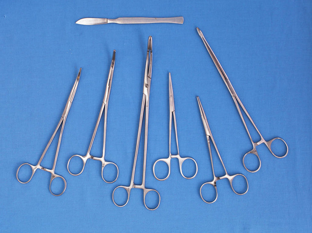 Ameliyat için masaya yerleştirilmiş neşter, pens ve cımbız gibi cerrahi aletler ve aletler. - Fotoğraf, Görsel