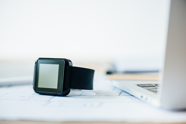 vergrote weergave van de smartwatch en laptop op werkplek - Foto, afbeelding
