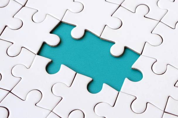 Close-up texture of a white jigsaw puzzle in assembled state with missing elements forming a blue pad for text. Copy space - Foto, Imagem