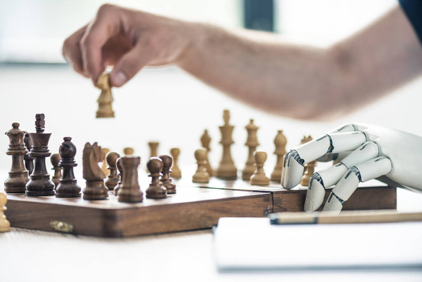 крупним планом вид людини і роботизована рука грає в шахи
 - Фото, зображення