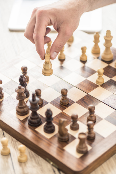 close-up partial view of person playing chess at wooden table - Photo, Image