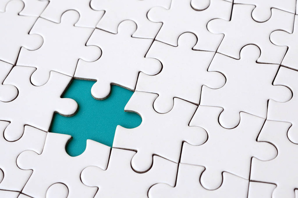Close-up texture of a white jigsaw puzzle in assembled state with missing elements forming a blue pad for text. Copy space - Photo, Image