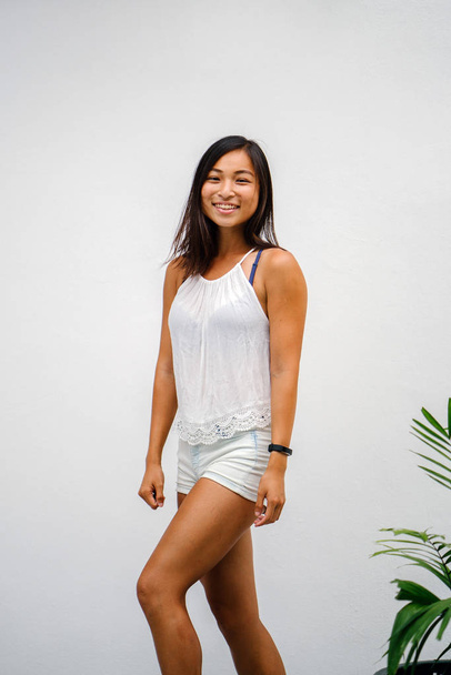 Portrait of a candid moment for an young, athletic and tanned Chinese Asian woman. She is smiling and is dress casually and comfortably. - Zdjęcie, obraz