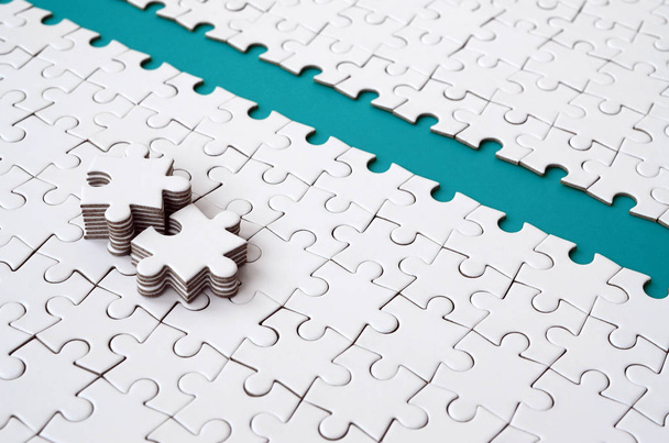 The blue path is laid on the platform of a white folded jigsaw puzzle. The missing elements of the puzzle are stacked nearby. Texture image with space for text - Photo, Image