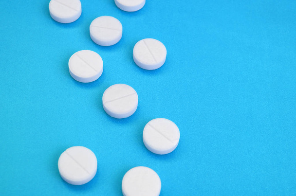 Muutama valkoinen tabletti on kirkkaan sinisellä pohjalla. Lääketieteellisten ja farmaseuttisten aiheiden taustakuva
 - Valokuva, kuva