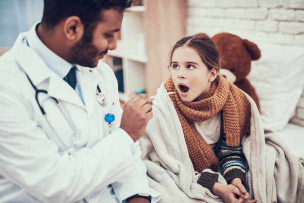 Indyjski lekarz widząc pacjentów w domu. Lekarz bada gardło dziewczynka z zimna. - Zdjęcie, obraz