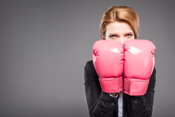 blonde businesswoman in suit and pink boxing gloves, isolated on grey - Foto, afbeelding