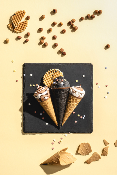 top view of black and white ice cream on black square on yellow  - Фото, изображение