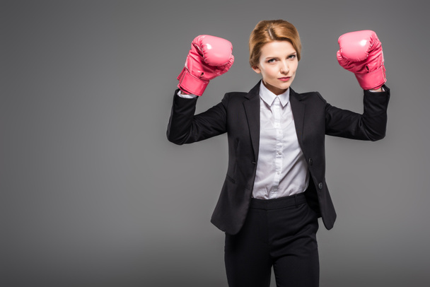 strong businesswoman in pink boxing gloves, isolated on grey - 写真・画像