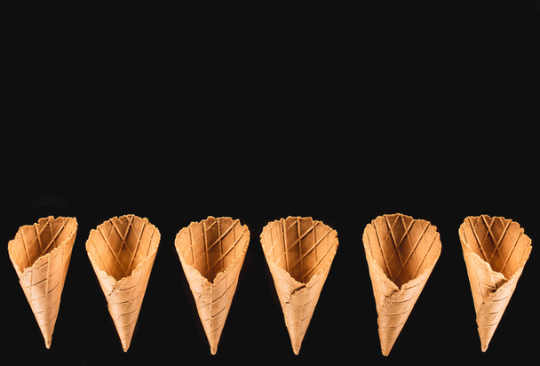 top view of row of appetizing ice cream cones isolated on black - Zdjęcie, obraz