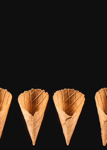 elevated view of row of ice cream cones isolated on black - Fotoğraf, Görsel
