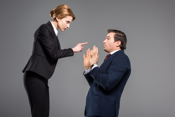 angry businesswoman quarreling and pointing at scared businessman, isolated on grey - Valokuva, kuva