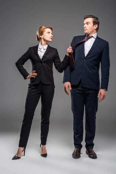 aggressive female leader holding tie of businessman, isolated on grey - Valokuva, kuva
