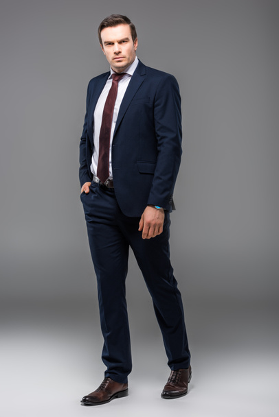 handsome confident businessman posing in suit, isolated on grey - Φωτογραφία, εικόνα