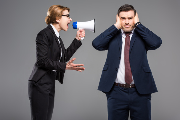 angry businesswoman with bullhorn screaming at businessman, isolated on grey, feminism concept - 写真・画像