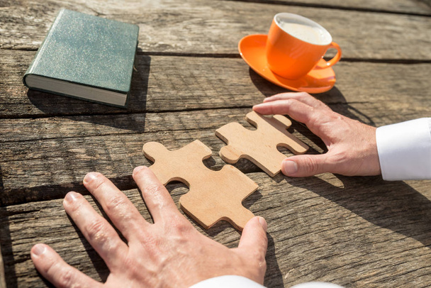 Hands of a businessman holding two jigsaw puzzle pieces - Photo, Image