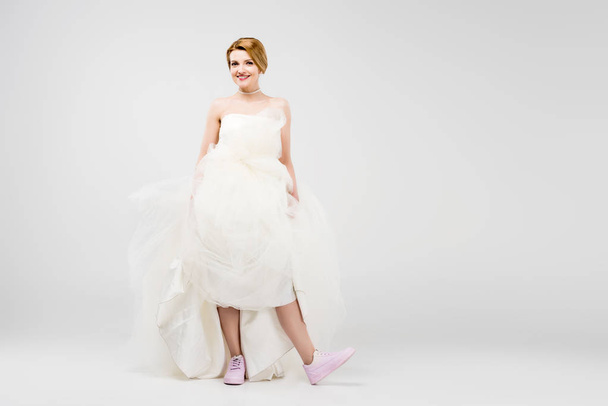 bride in white wedding dress and pink sneakers, isolated on grey, feminism concept - Fotografie, Obrázek