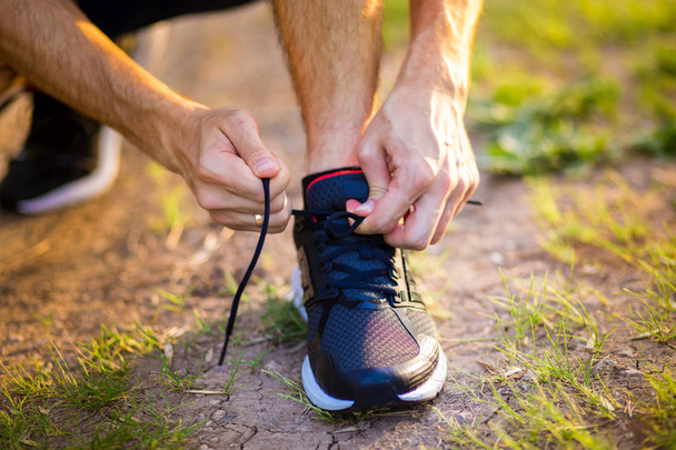 Man tying running shoes. Healthy lifestyle. Athlete tying laces for jogging on road in barefoot running shoes. Runner getting ready for training - Zdjęcie, obraz