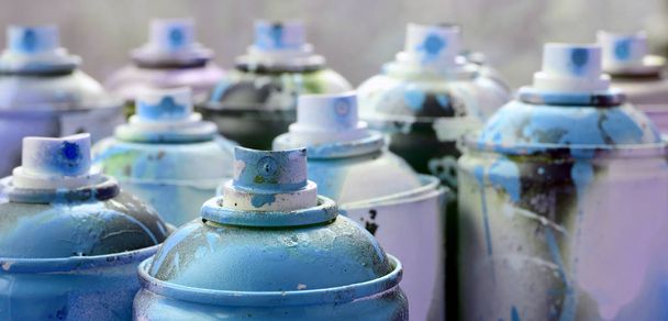 A lot of dirty and used aerosol cans of bright blue paint. Macro photograph with shallow depth of field. Selective focus on the spray nozzle - Photo, Image