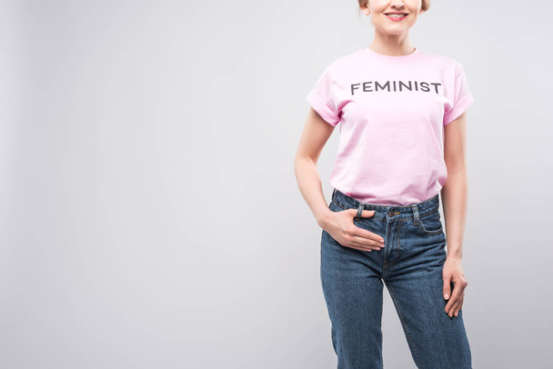 vista recortada de mulher sorridente em camiseta feminista rosa, isolada em cinza
 - Foto, Imagem