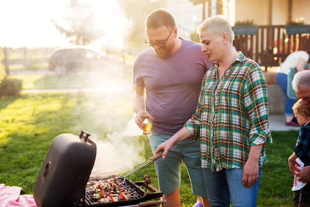 cheerful man and woman grilling in a backyard - Foto, Imagem