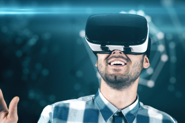 A young man with a beard in glasses of virtual reality on a technological background - Photo, Image
