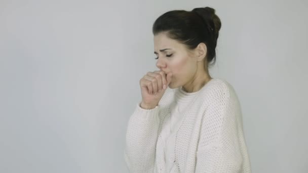 Ill girl with runny nose in white jacket with temperature coughs in front of white background - Materiał filmowy, wideo