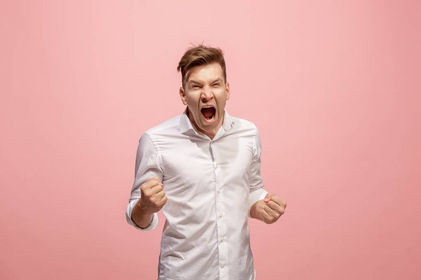 The young emotional angry man screaming on pink studio background - Photo, image