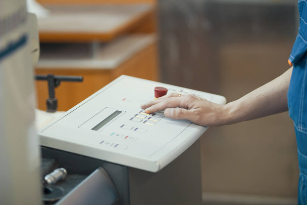 Manos del trabajador presiona los botones en el panel de control de la máquina de impresión
 - Foto, Imagen