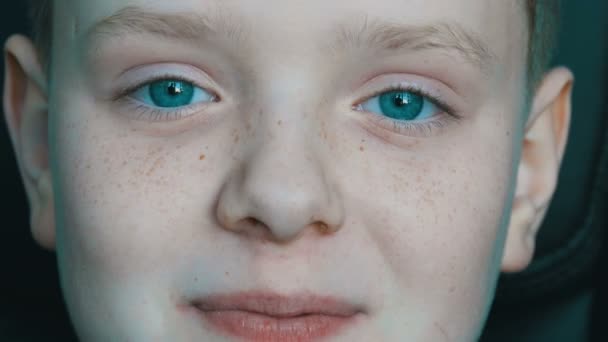 Vrolijke blonde jongen met een tiener met sproeten op zijn gezicht en ongewone turquoise ogen kijken camera en gelukkig gek - Video