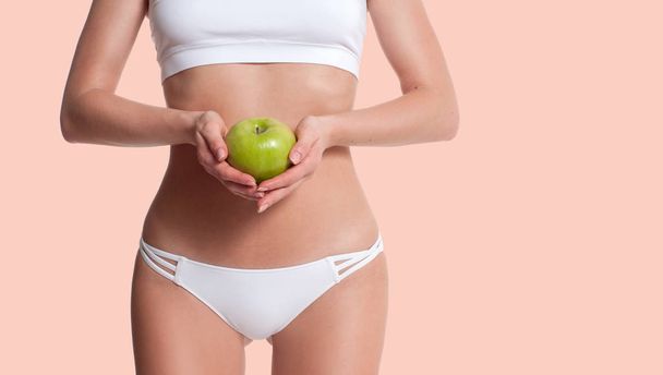 Diet. Beautiful slim woman with perfect sporty body holding apple. - Zdjęcie, obraz