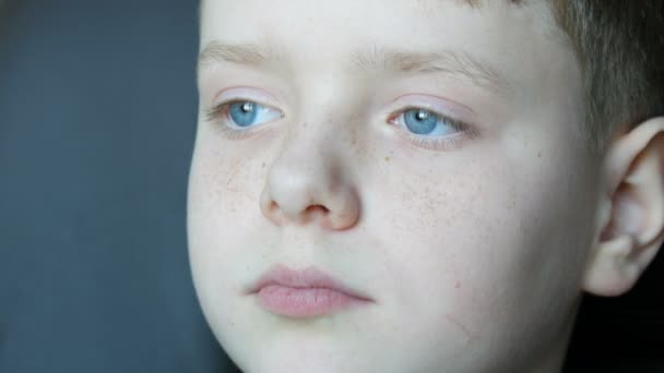Face of beautiful teenager with freckles close-up view. A boy with blue eyes looking into the distance - Footage, Video
