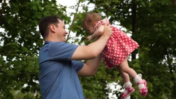 Szczęśliwy tata zamienia jego córka na jego ręce chodzić z nią w zielonym parku. - Materiał filmowy, wideo