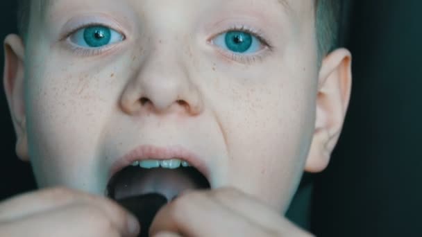 Szeplős szőke fiú tinédzser eszik csokoládé közelről - Felvétel, videó