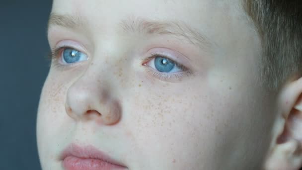 Doordachte triest blauwe ogen van blonde jongen tiener met rode vlekjes op zijn gezicht en lange witte wimpers die de verte kijkt - Video